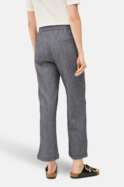 Pantalon bleu texturé par CECIL, avec poches arrières et portées avec des sandales noires vernies.
