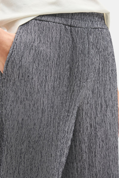 Pantalon bleu texturé de CECIL, avec ceinture élastique et poche latérale, porté avec un t-shirt blanc.
