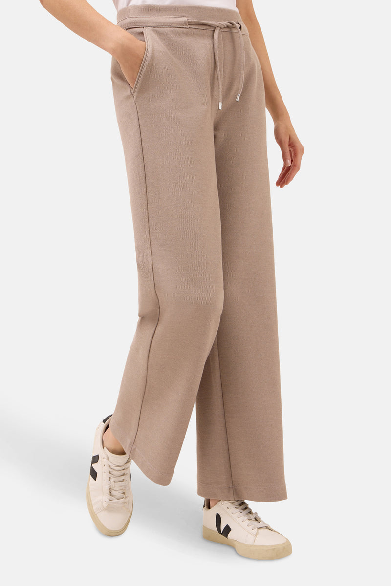 Taupe broek van CECIL, met trekkoord en zijzakken, gedragen met crèmekleurige sneakers.