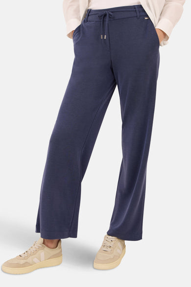 Pantalon bleu de CECIL, coupe décontractée, avec cordon de serrage et poches latérales, porté avec des baskets beiges.
