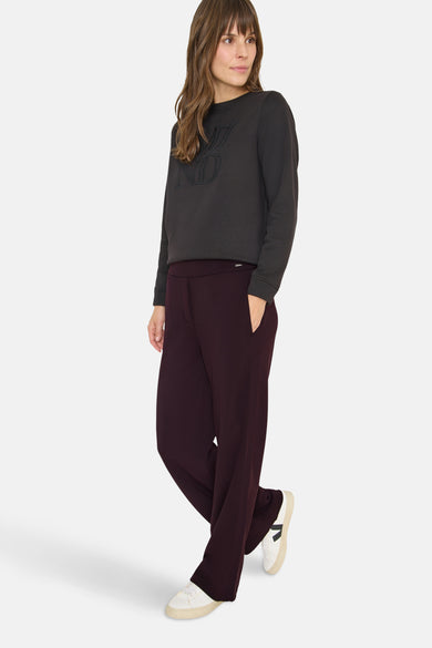 Pantalon de costume mauve de CECIL, porté avec un pull gris à motif et des baskets blanches.
