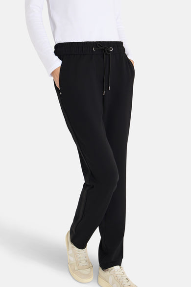 Pantalon de costume noir CECIL avec cordon de serrage, détail de bande latérale et chaussures de sport beiges.