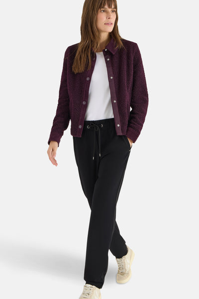 Pantalon de costume noir de CECIL, porté avec un t-shirt blanc et un gilet violet en bouclette.
