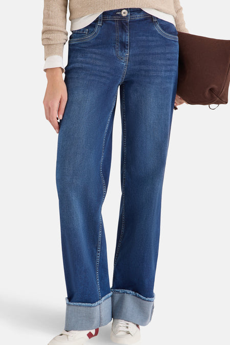 Jean bleu denim par CECIL avec revers contrastés, porté avec un pull beige.