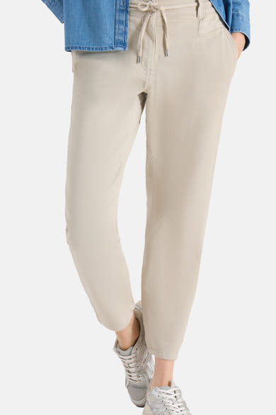 Jogging beige de CECIL, coupe décontractée avec cordon de serrage et poches pratiques, porté avec une chemise en jean.
