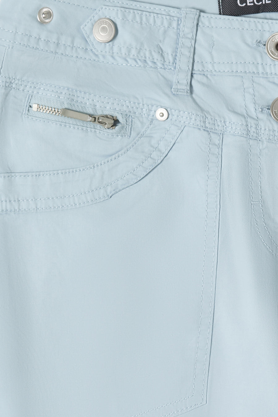 Pantalon cargo bleu clair de CECIL avec poche zippée, boutons métalliques et surpiqûres, vue rapprochée.