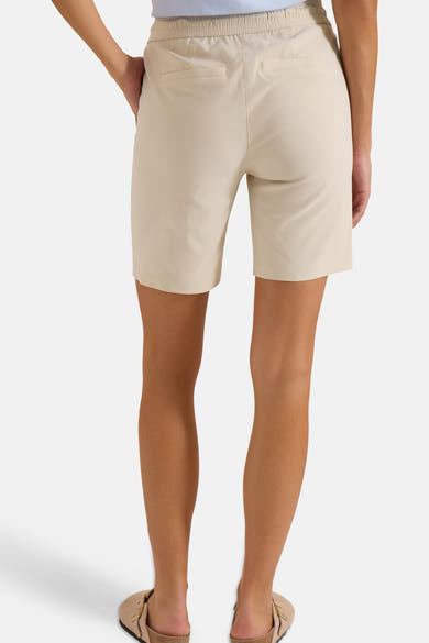 Bermuda beige de CECIL avec taille élastique et deux poches arrière passepoilées, porté avec des mules.