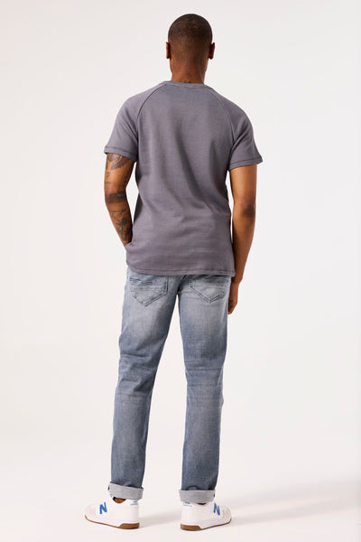 T-shirt gris à manches courtes de GARCIA, avec motif texturé, porté avec un jean bleu clair et des baskets blanches.