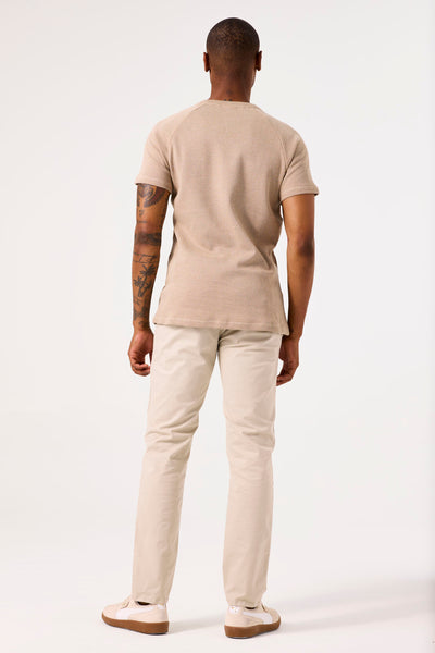 Beige T-shirt met korte mouwen van GARCIA, met een gestructureerd patroon van horizontale strepen, gedragen met een lichte broek en sneakers.