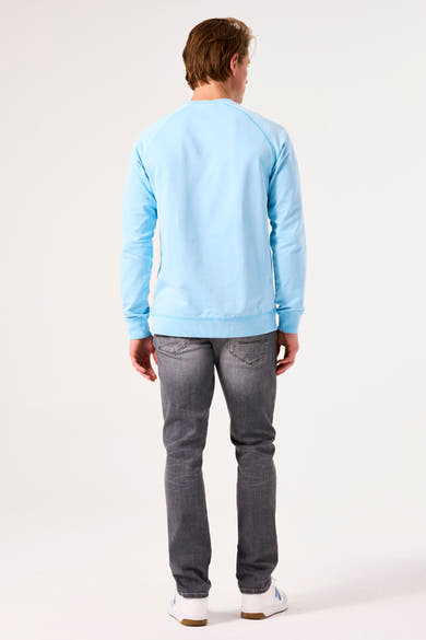Turquoise sweater by GARCIA, long raglan sleeves, worn with grey jeans and white sneakers, back view.