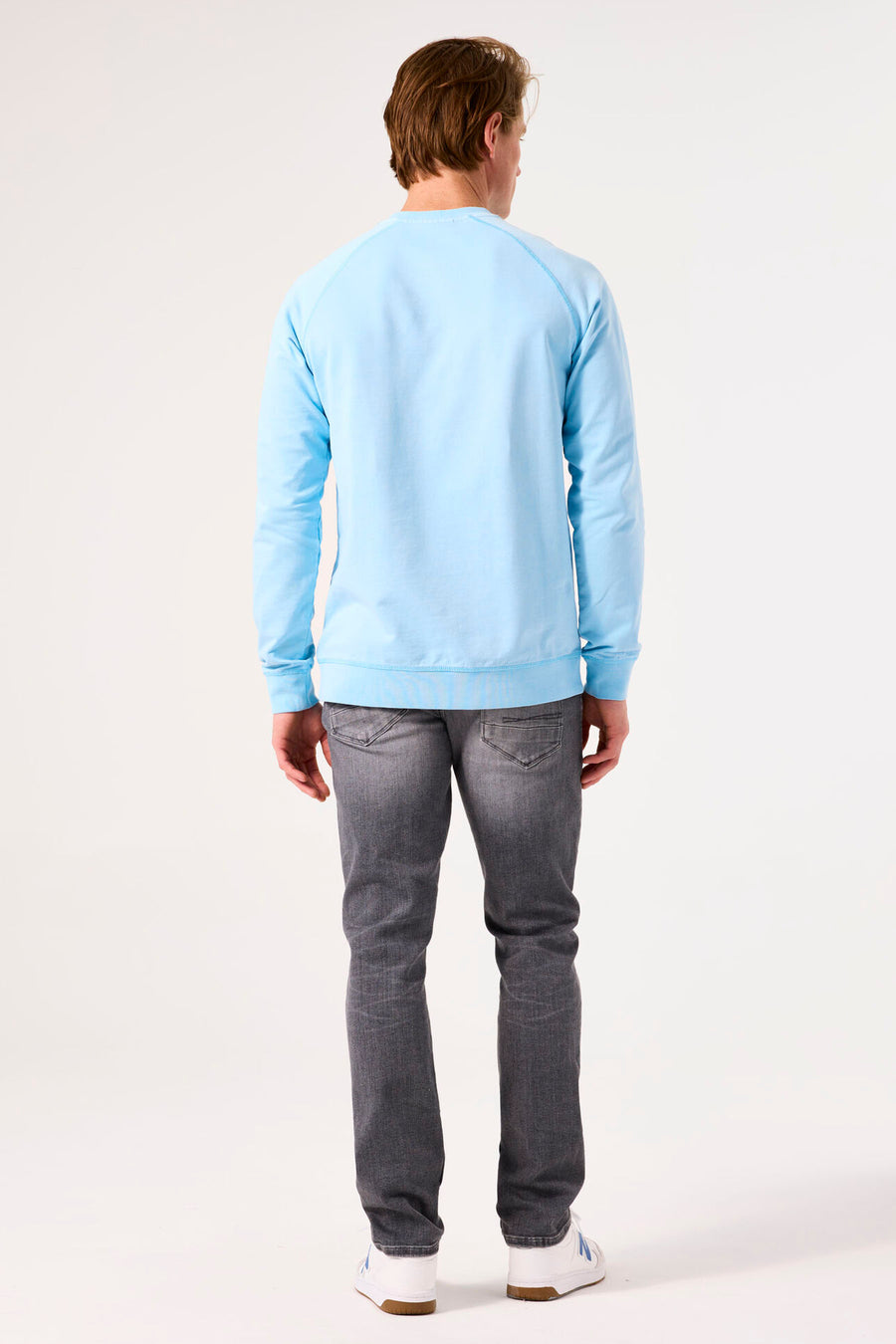 Turquoise sweater by GARCIA, long raglan sleeves, worn with grey jeans and white sneakers, back view.