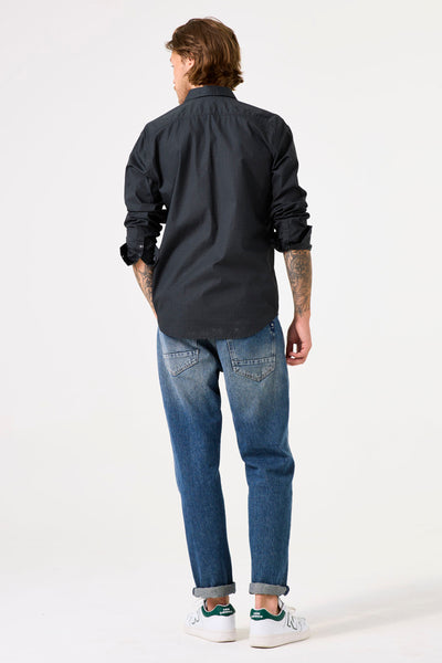 Chemise à manches longues grise de GARCIA, avec motifs discrets, portée avec un jean bleu et des baskets blanches.