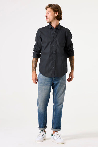 Chemise à manches longues grise de GARCIA, avec des motifs subtils, portée avec un jean bleu et des baskets blanches.