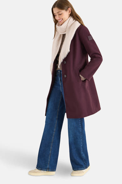 Écharpe beige de CECIL, avec des franges décoratives, portée avec un manteau bordeaux, un jean ample et des baskets.