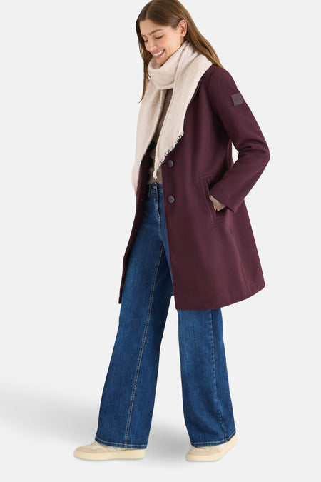 Écharpe beige de CECIL, avec des franges décoratives, portée avec un manteau bordeaux, un jean ample et des baskets.