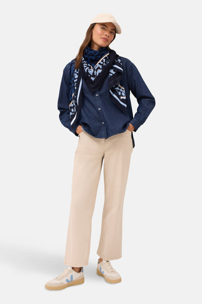Multikleurige sjaal van CECIL, met een blauw abstract patroon en gedragen met een spijkerblouse en een beige broek.