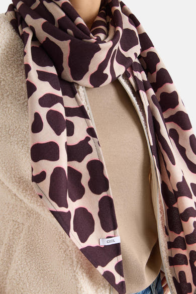 Foulard multicolore de CECIL avec motif abstrait marron et beige, porté autour du cou avec une veste en teddy beige.
