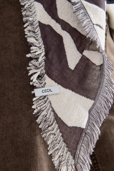 Écharpe multicolore de CECIL, à motif abstrait et à franges, posée sur un tissu marron.
