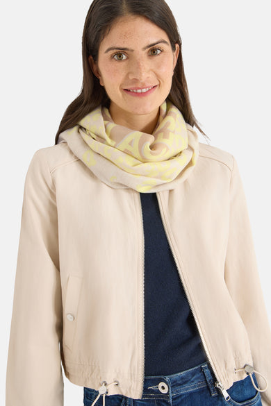 Zilveren sjaal van CECIL, met geel en beige bloemenpatroon, gedragen met een beige jas.