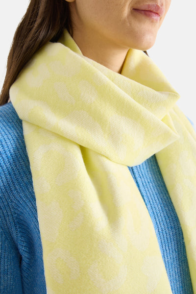 Écharpe jaune clair imprimée par CECIL, nouée autour du cou avec un pull bleu en tricot visible.
