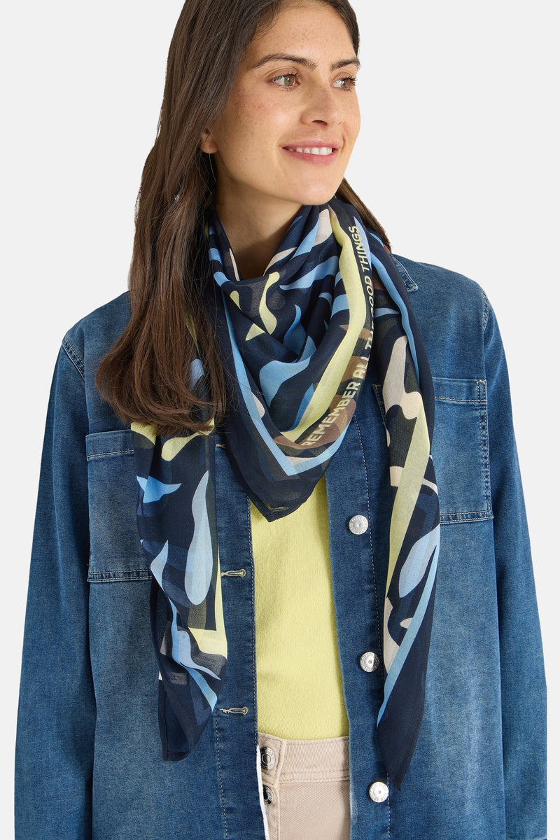 Foulard multicolore de CECIL, avec motif abstrait et citation inspirante, porté avec une veste en jean et un pull jaune.
