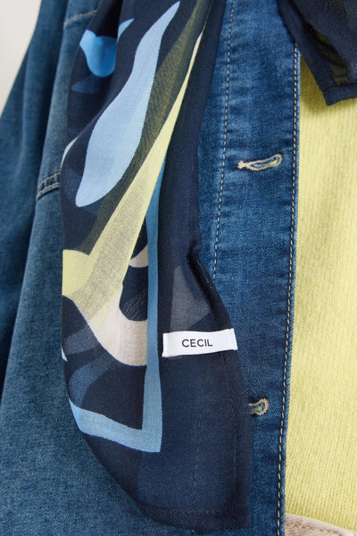 Multikleuren sjaal van CECIL, met abstract patroon in blauwe en gele tinten, gedragen met een spijkerjasje.