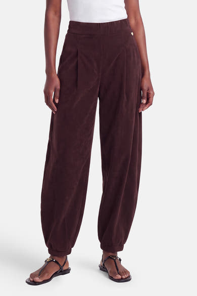 Pantalon violet en velours élastique par AMELIE ET AMELIE, coupe ample avec ourlet élastiqué, vue de face sur modèle portant sandales noires