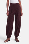 Pantalon violet en velours élastique par AMELIE ET AMELIE, coupe ample avec ourlet élastiqué, vue de face sur modèle portant sandales noires