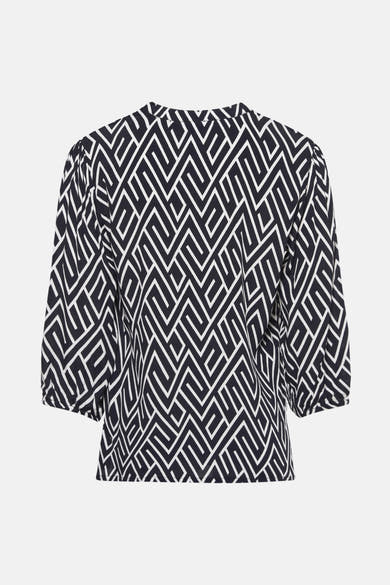 Donkerblauwe blouse ZABAIONE met wit geometrisch patroon over het hele kledingstuk, driekwart pofmouwen.