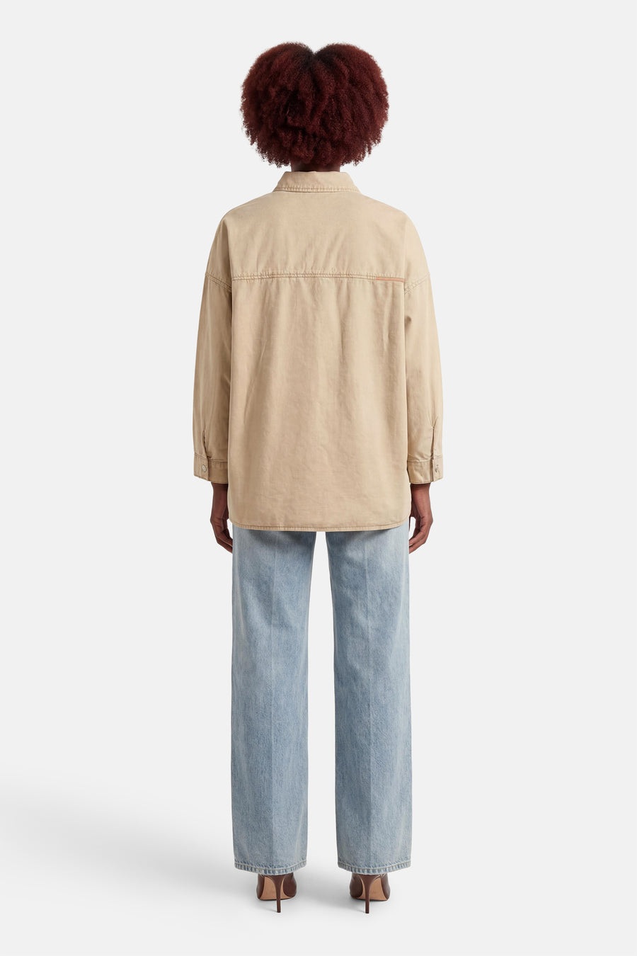 Chemise beige à manches longues d'ADORE, vue de dos, avec détail de couture et portée avec un jean et des talons marron.
