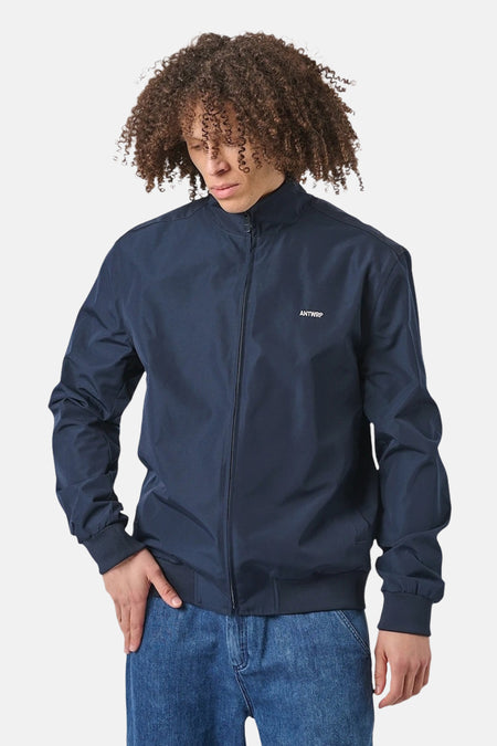 Blauwe regenjas van ANTWRP, met een ritssluiting over de hele lengte en een klein geborduurd logo.