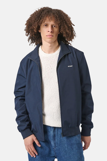 Blauwe regenjas van ANTWRP, gedragen door een man met een witte trui en een spijkerbroek.