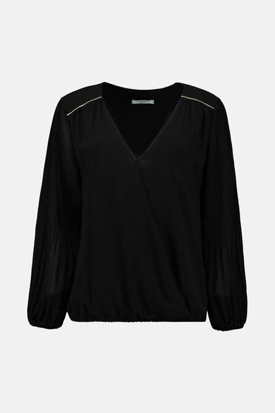 Blouse noire à manches longues de Zabaione, avec des détails plissés et des accents dorés aux épaules.
