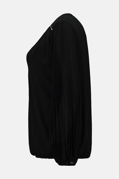 Blouse noire à manches longues de Zabaione, avec détail plissé sur l'épaule et manches bouffantes.