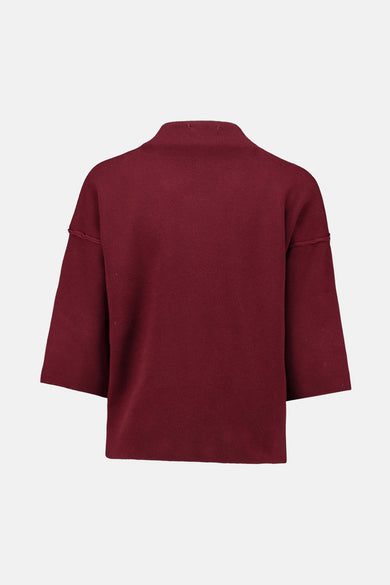 Pull à col roulé rouge de Zabaione, avec des manches courtes amples et une texture tricotée.