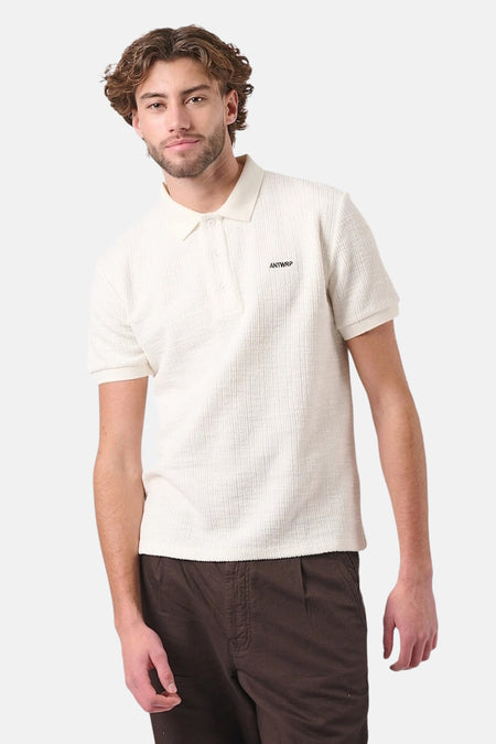 Wit poloshirt met korte mouwen van ANTWRP, textuurstof, gedragen met een bruine broek.