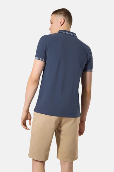 Polo bleu marine d'ANTWRP, manches courtes à rayures blanches, porté avec un short beige, vue arrière.
