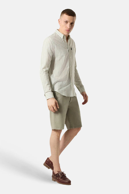 Chemise à manches longues verte par ANTWRP, à rayures verticales, portée avec un short kaki et des chaussures bateau.