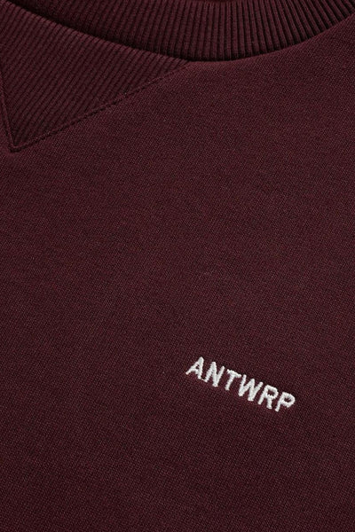Bordeaux crewneck sweatshirt with ribbed neckline and white embroidered "ANTWRP" logo, close-up front view