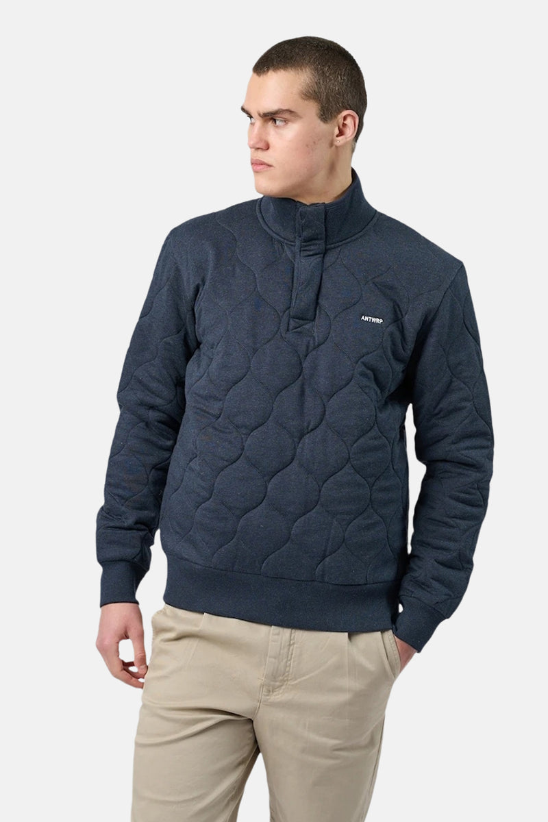 Blauwe trui met opstaande kraag van ANTWRP met ruitvormig doorgestikt patroon en beige chino broek.