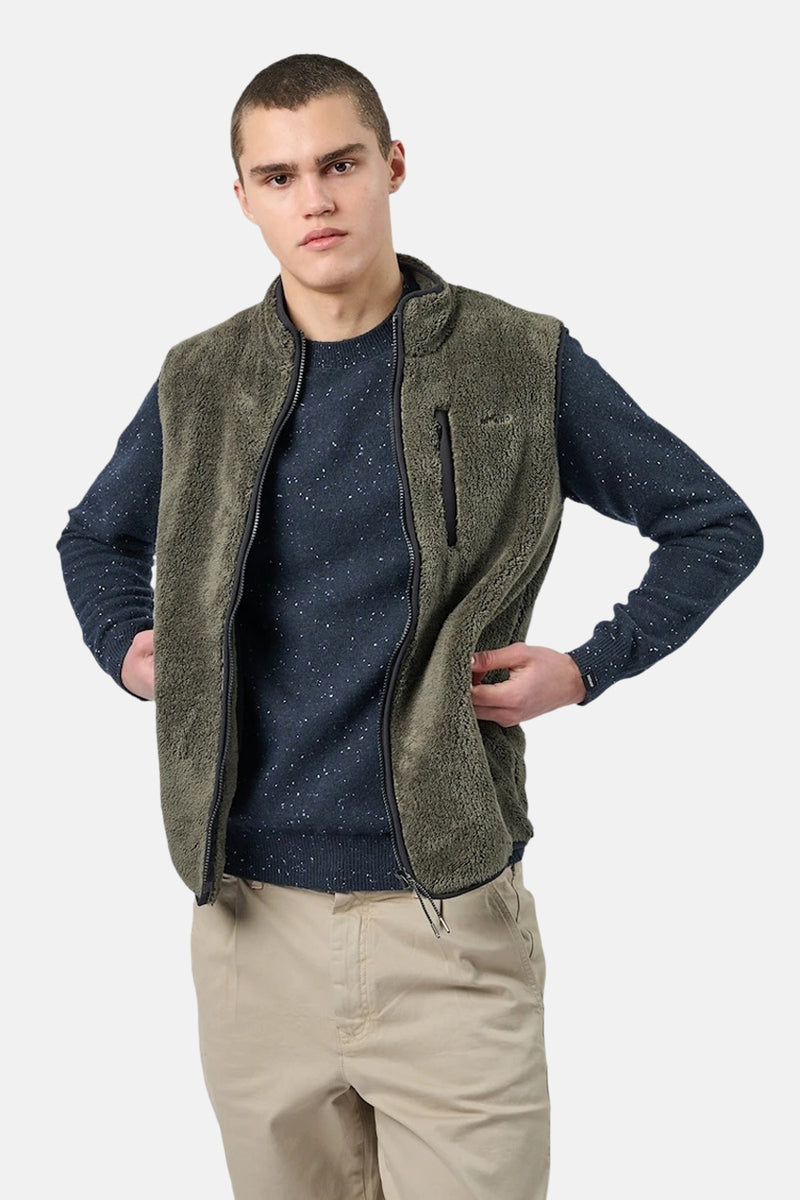Veste sans manches en polaire kaki d'ANTWRP, portée sur un pull bleu marine moucheté et un pantalon beige.