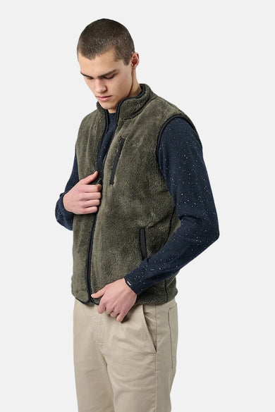 Polaire kaki de ANTWRP, à fermeture éclair, porté sur un pull bleu marine à pois, avec un pantalon beige.