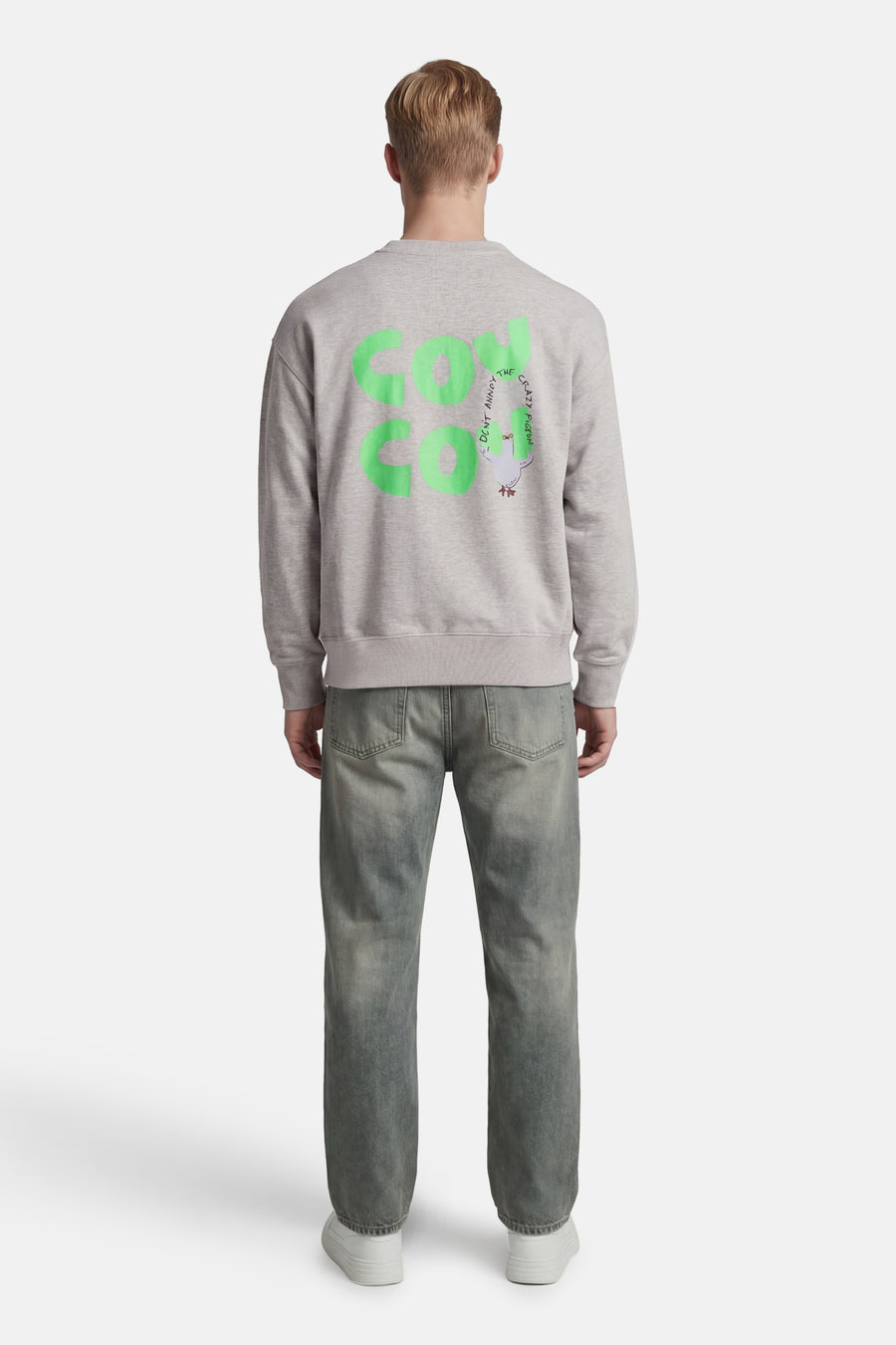 Grijze rondehals sweatshirt van ANTWRP, met een grafische print op de rug, gedragen met een verbleekte spijkerbroek en witte sneakers.