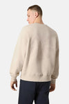 Sweat-shirt écru de ANTWRP, avec un motif ton sur ton dans le dos, porté avec un pantalon bleu marine.
