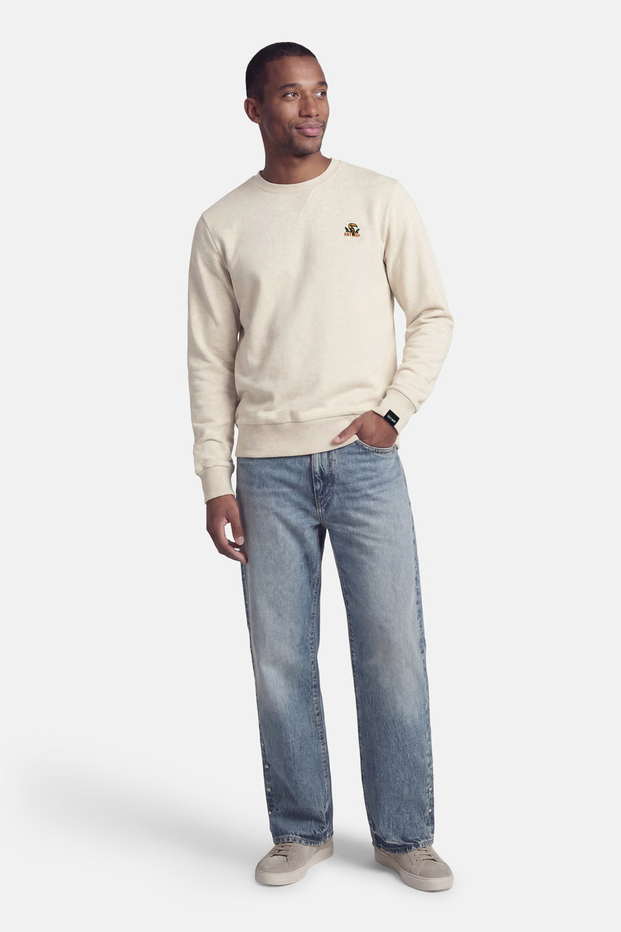 Sweat-shirt beige van ANTWRP, avec un petit logo brodé sur la poitrine, porté avec un jean et des baskets décontractées.