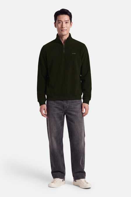 Fleece vert à capuche zippée par ANTWRP, coupe droite, logo discret sur poitrine, porté avec jeans gris et baskets blanches, vue de face.