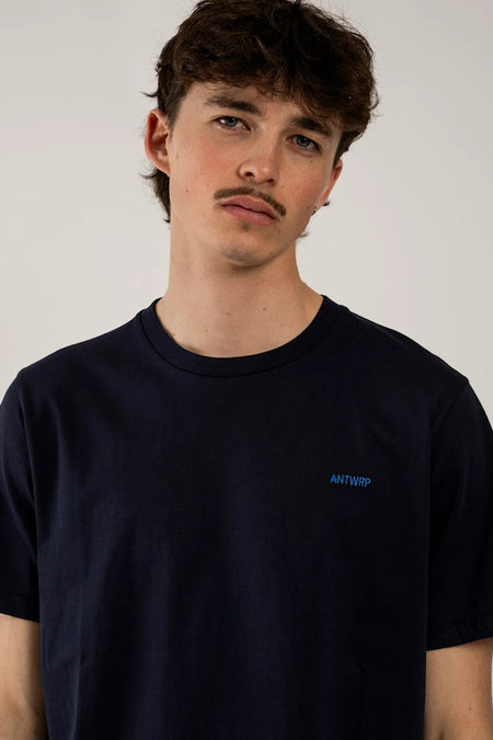 Blauw T-shirt met korte mouwen van ANTWRP, gedragen door een man met een snor.