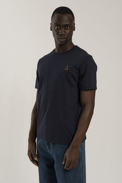 Navy blue short-sleeve t-shirt by Any Old Iron with small embroidered logo on chest, worn with dark denim jeans, front view.