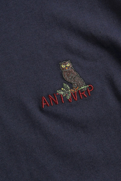 Navy blue short-sleeve t-shirt with embroidered owl and red "ANTWERP" text, close-up chest view