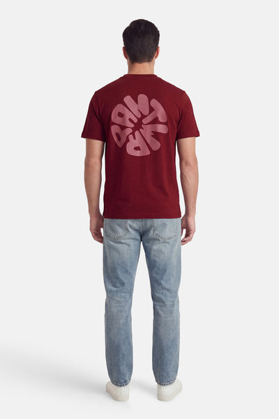 T-shirt à manches courtes rose, par ANTWRP, avec motif graphique au dos, porté avec un jean et des chaussures blanches.